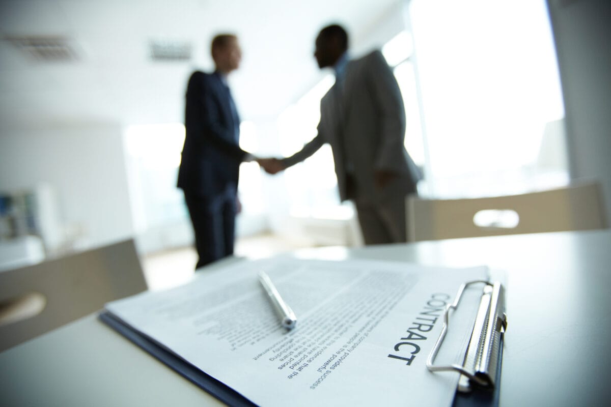 two men shaking hand with contract in frame