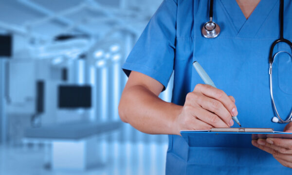 midsection of doctor writing on clipboard