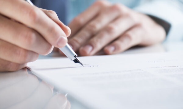 closeup of hand signing contract